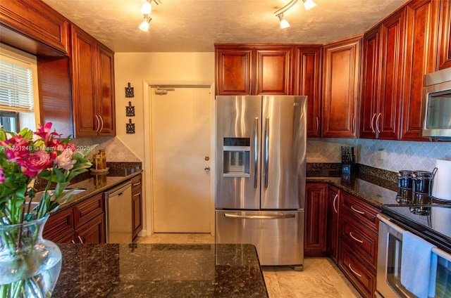 kitchen featuring appliances with stainless steel finishes, dark stone counters, and decorative backsplash