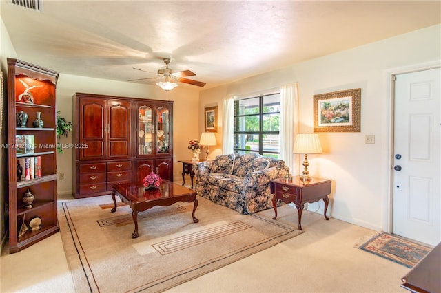 living room with light carpet, baseboards, visible vents, and a ceiling fan