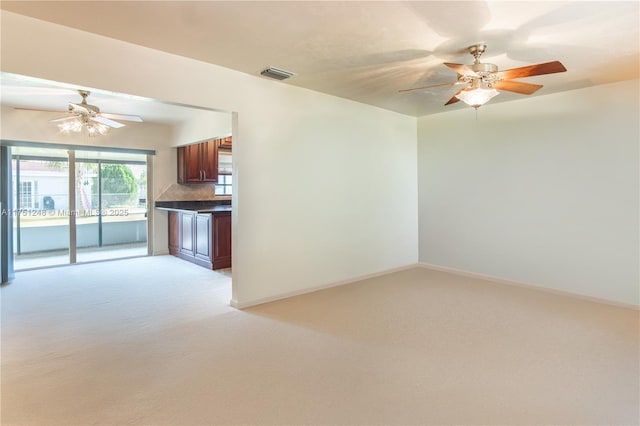 interior space with dark countertops, light colored carpet, visible vents, backsplash, and ceiling fan