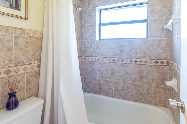 full bath with toilet, shower / bath combo, and tile walls