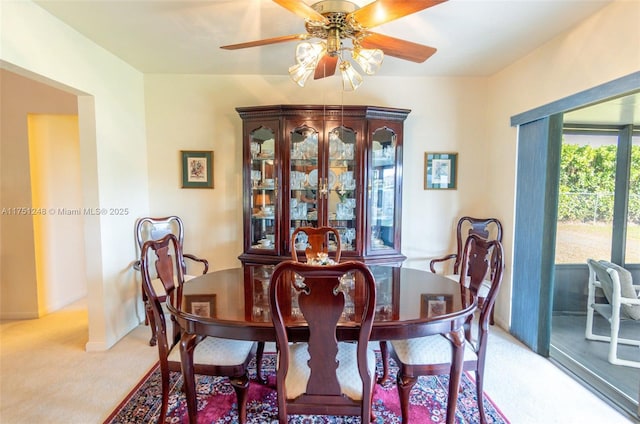 dining room with a ceiling fan, light carpet, and baseboards