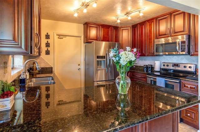 kitchen with dark stone countertops, tasteful backsplash, appliances with stainless steel finishes, and a sink