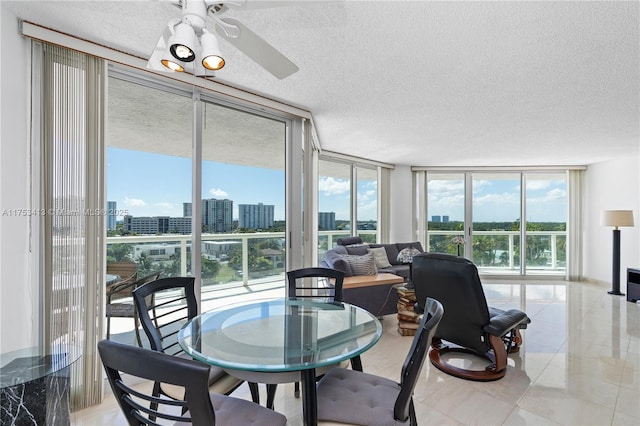 dining room featuring a view of city, ceiling fan, a wall of windows, and a textured ceiling