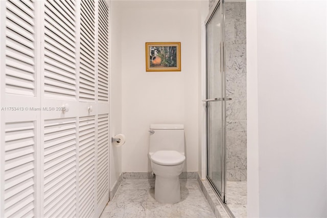 bathroom featuring marble finish floor, a stall shower, toilet, and baseboards