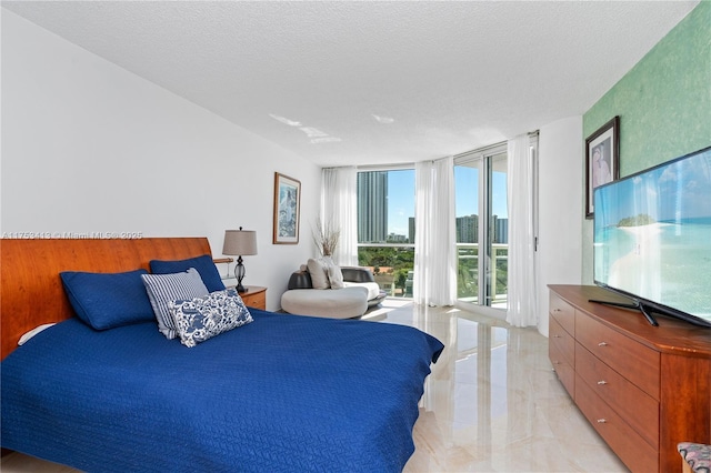 bedroom with marble finish floor, access to outside, floor to ceiling windows, and a textured ceiling