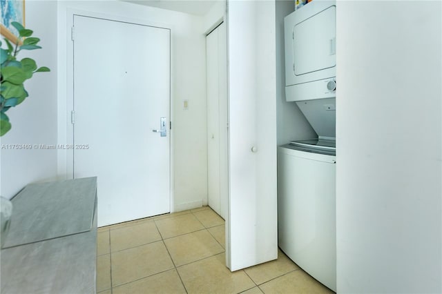 laundry room with laundry area, stacked washing maching and dryer, and light tile patterned flooring