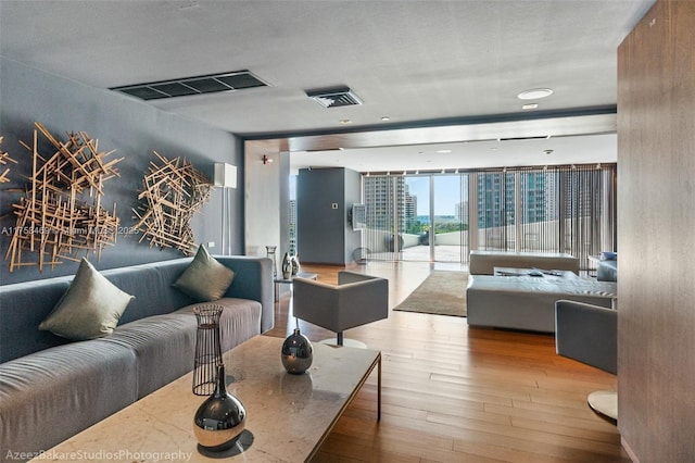 living room with floor to ceiling windows, visible vents, and hardwood / wood-style floors