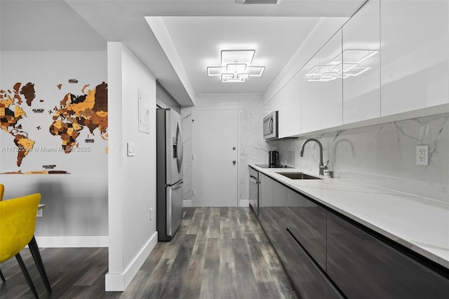 kitchen with a sink, appliances with stainless steel finishes, decorative backsplash, dark wood-style floors, and modern cabinets