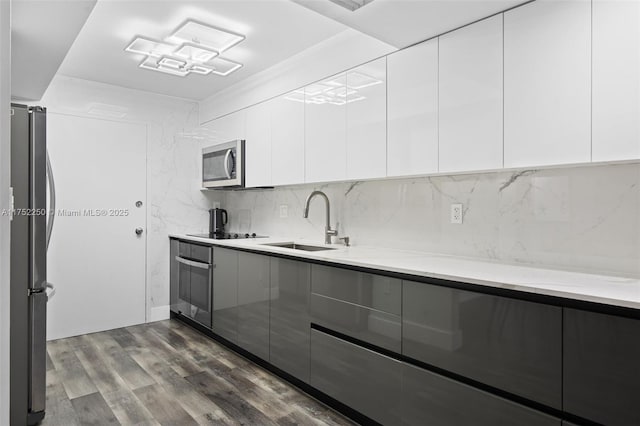 kitchen with dark wood finished floors, modern cabinets, stainless steel appliances, and a sink