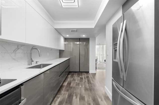 kitchen featuring gray cabinetry, a sink, backsplash, modern cabinets, and stainless steel fridge