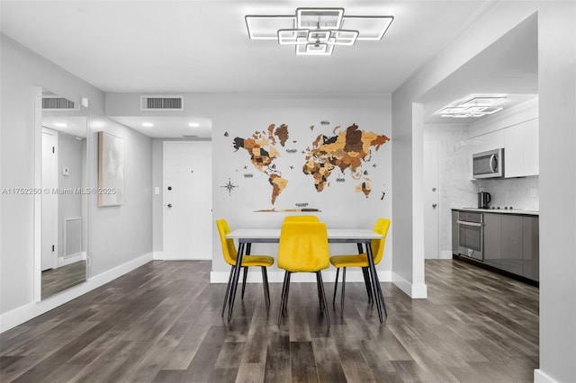 dining space with baseboards, visible vents, and dark wood finished floors