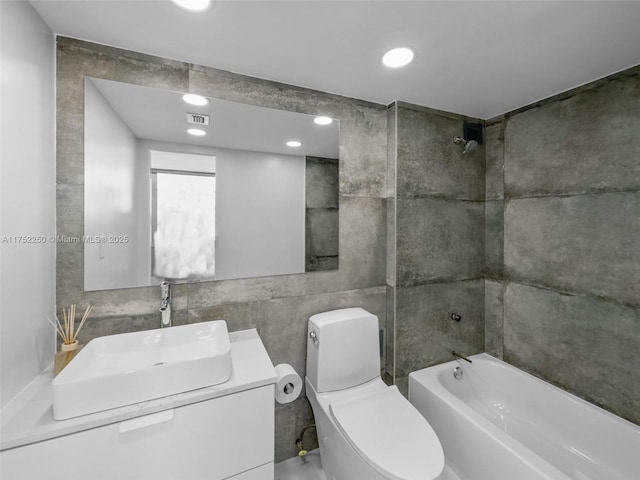 full bathroom with visible vents, toilet, tub / shower combination, vanity, and tile walls