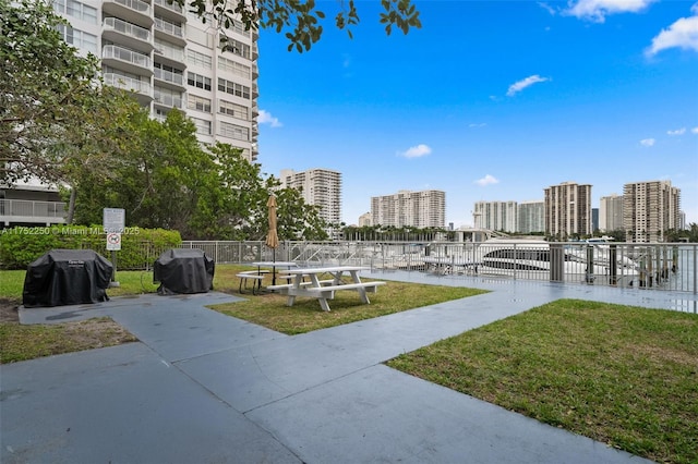 view of home's community featuring a view of city, a lawn, and fence