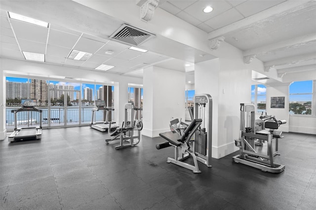 workout area with a paneled ceiling, visible vents, and baseboards