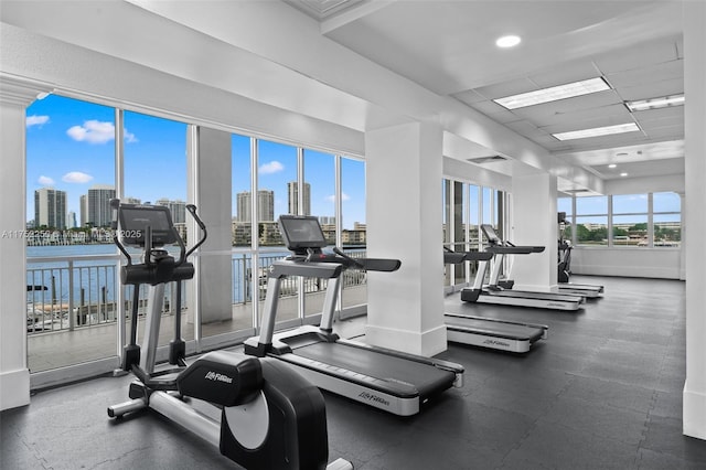 workout area featuring baseboards, visible vents, a paneled ceiling, and a city view