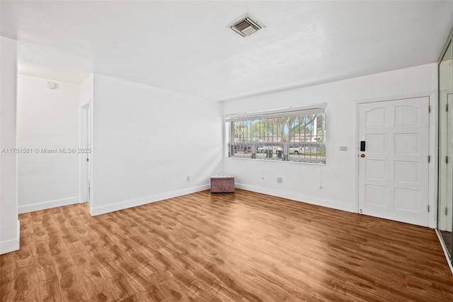 empty room with baseboards, visible vents, and wood finished floors