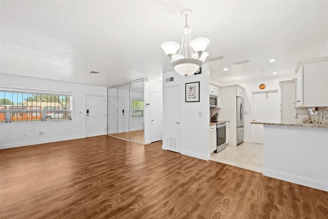 unfurnished living room featuring light wood finished floors, recessed lighting, visible vents, a chandelier, and baseboards