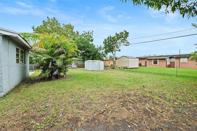 view of yard featuring a shed, an outdoor structure, and fence