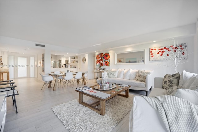 living area with light wood finished floors, visible vents, and recessed lighting