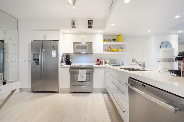 kitchen with open shelves, light countertops, appliances with stainless steel finishes, white cabinetry, and a sink