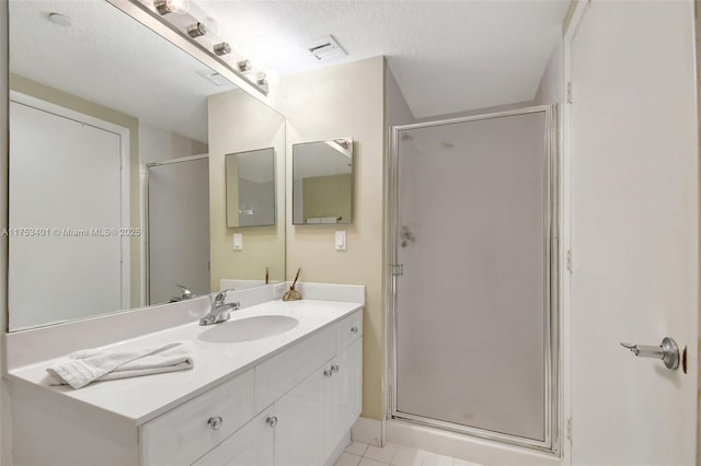 full bathroom with a stall shower, visible vents, a textured ceiling, and vanity