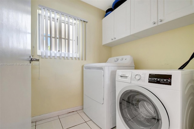 washroom with cabinet space, washing machine and dryer, baseboards, and light tile patterned flooring