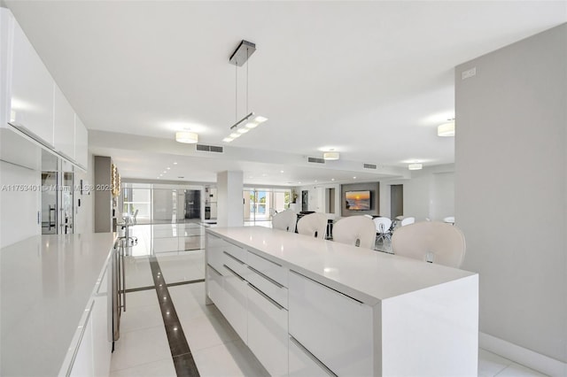 kitchen with light tile patterned floors, a spacious island, modern cabinets, light countertops, and white cabinetry