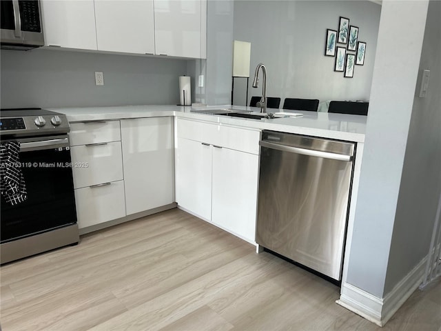 kitchen featuring light countertops, appliances with stainless steel finishes, a sink, and white cabinetry