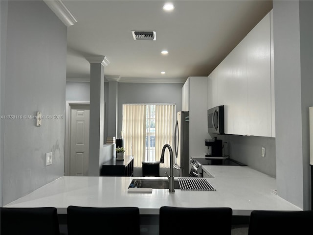 kitchen with a peninsula, visible vents, appliances with stainless steel finishes, and a sink