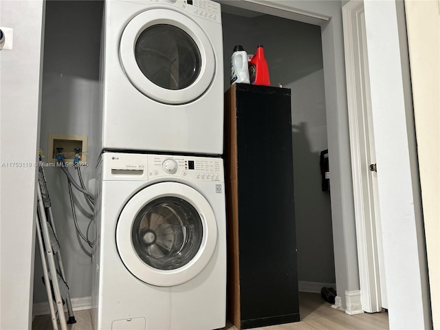 washroom featuring laundry area, stacked washer and clothes dryer, and light wood-style floors