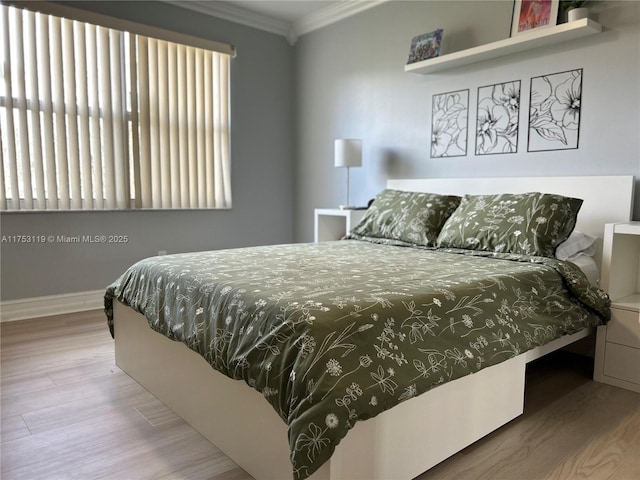 bedroom with ornamental molding, wood finished floors, and baseboards