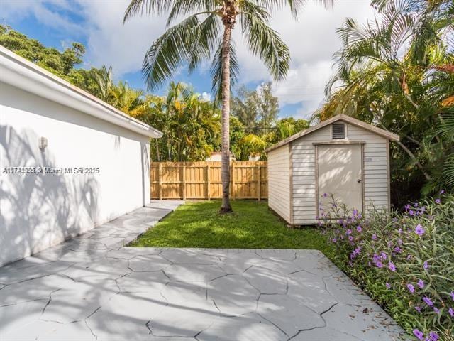 view of yard with a shed, a patio area, fence, and an outdoor structure