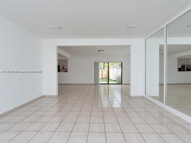 spare room featuring light tile patterned floors and baseboards