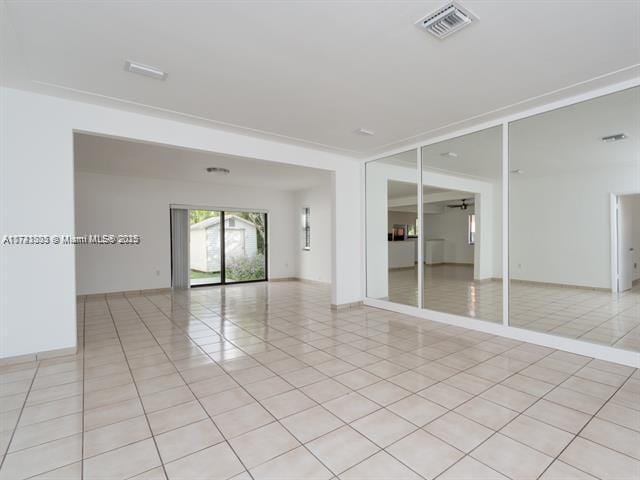 unfurnished room with light tile patterned floors, baseboards, visible vents, and ceiling fan