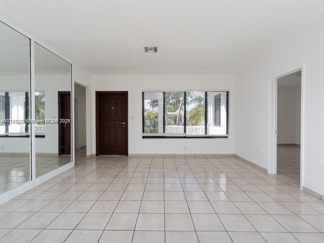 spare room with baseboards, visible vents, and light tile patterned flooring