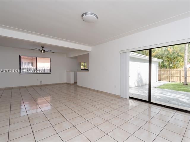 empty room with a ceiling fan, baseboards, and light tile patterned floors