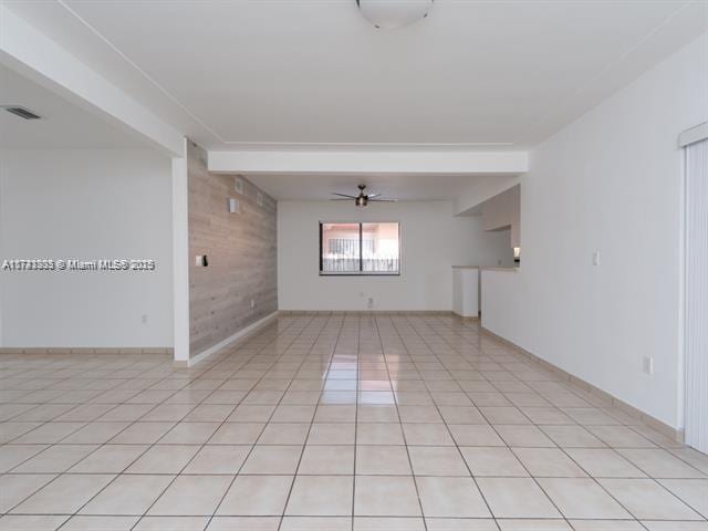 empty room featuring visible vents, ceiling fan, wood walls, beam ceiling, and light tile patterned flooring