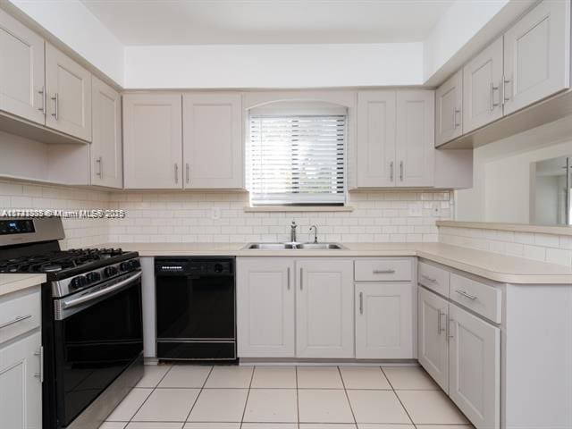 kitchen featuring black dishwasher, light countertops, a sink, and gas stove