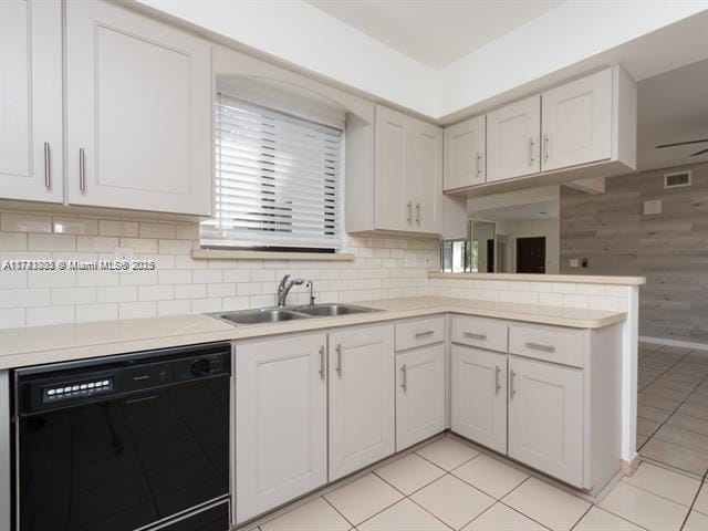 kitchen featuring black dishwasher, tasteful backsplash, a peninsula, light countertops, and a sink