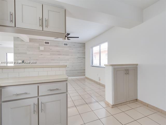 kitchen featuring a ceiling fan, light countertops, baseboards, and light tile patterned floors