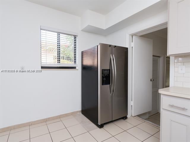 kitchen featuring light tile patterned floors, white cabinetry, stainless steel refrigerator with ice dispenser, and light countertops