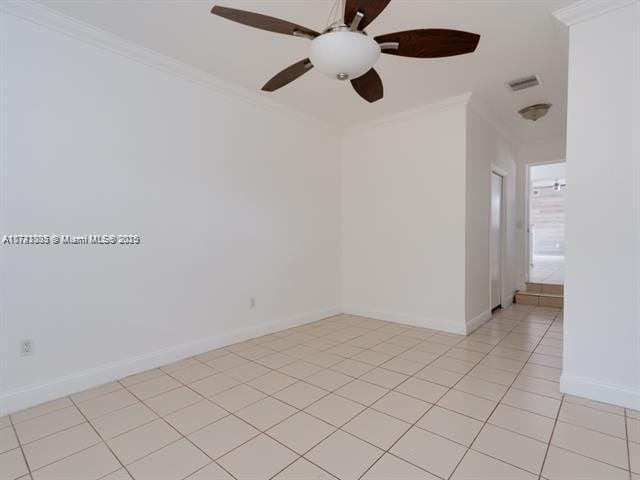 spare room featuring light tile patterned floors, visible vents, ornamental molding, and baseboards