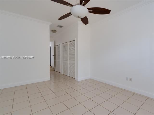 empty room with visible vents, baseboards, crown molding, and light tile patterned flooring