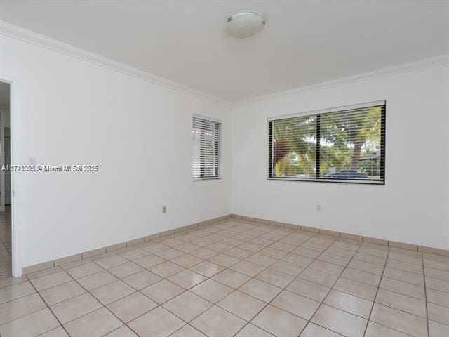 unfurnished room with light tile patterned floors and ornamental molding