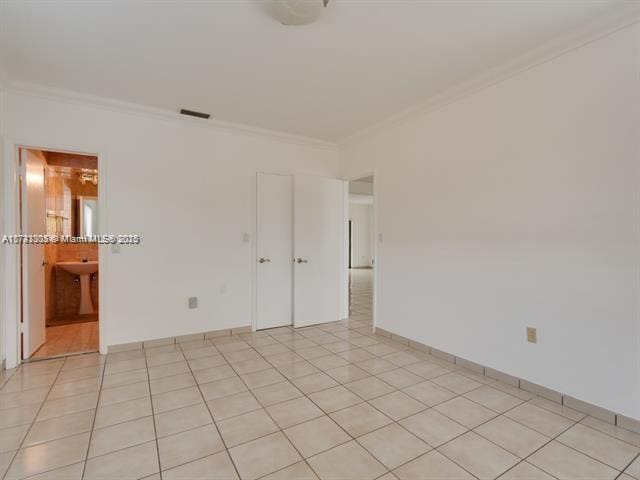 spare room with ornamental molding, visible vents, baseboards, and light tile patterned floors