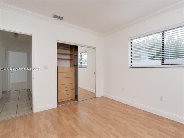 unfurnished bedroom featuring light wood-type flooring, visible vents, and crown molding