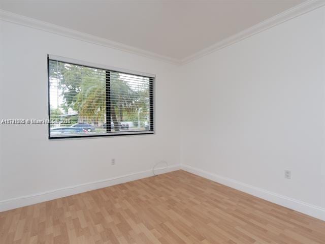 unfurnished room featuring light wood-style floors, crown molding, and baseboards