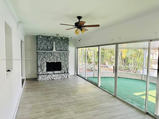 unfurnished living room featuring ceiling fan, a fireplace, crown molding, and wood finished floors