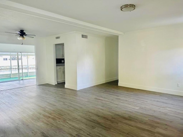 spare room with dark wood-style floors, ceiling fan, visible vents, and baseboards