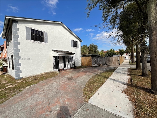 view of side of property with fence and stucco siding